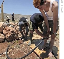 Jewish settlers wash cement off their feet after laying foundation of new building in West Bank outpost of Maoz Esther, 28 May 2009