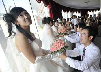 Chinese brides receive the bouquet of flowers from their grooms during a mass wedding ceremony in Wuhan, central China's Hubei province on 08 August 2008. [Agencies] 
