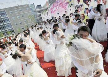 Chinese couples kiss during a mass wedding ceremony in Wuhan, central China's Hubei province on 08 August 2008. [Agencies] 