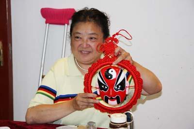 Xue Lili displays a fabric Peking Opera facial mask to the journalists who visit the Shichahai Sweet Home in Xicheng District, Beijing. [Photo: CRIENGLISH.com]